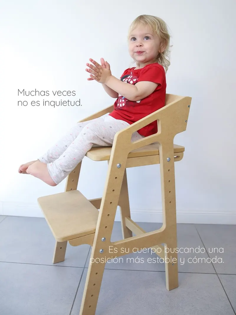Nena dibujando en la mesa, sentada en una silla evolutiva de roble
