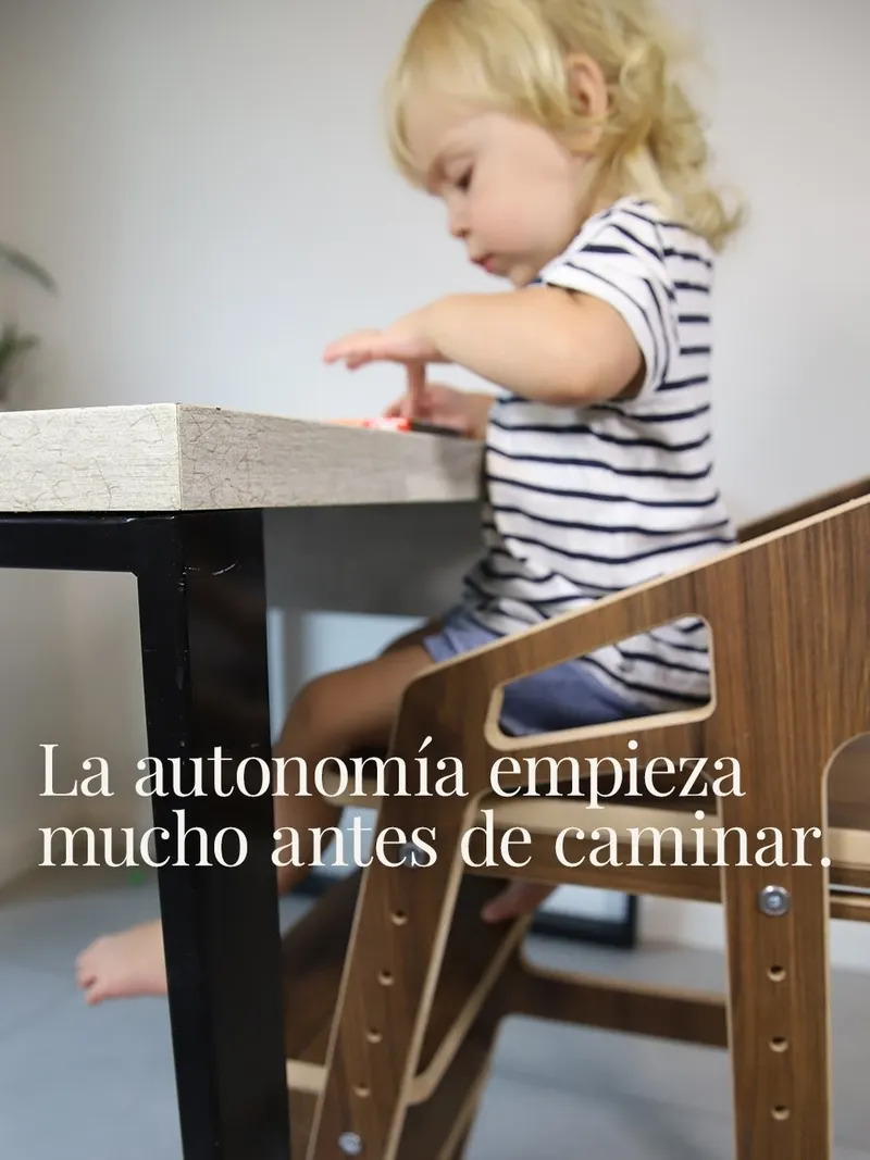 Nene comiendo en la mesa familiar, sentado en una silla evolutiva de nogal