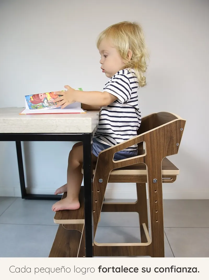 Nene comiendo en la mesa familiar, sentado en una silla evolutiva de nogal